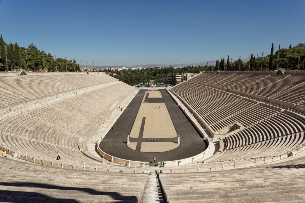 Panathenaic Stadium in Athens, with marble seating tiers around the running track, under a clear blue sky