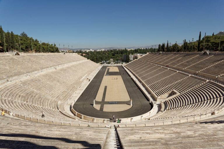 Panathenaic Stadium in Athens, with marble seating tiers around the running track, under a clear blue sky
